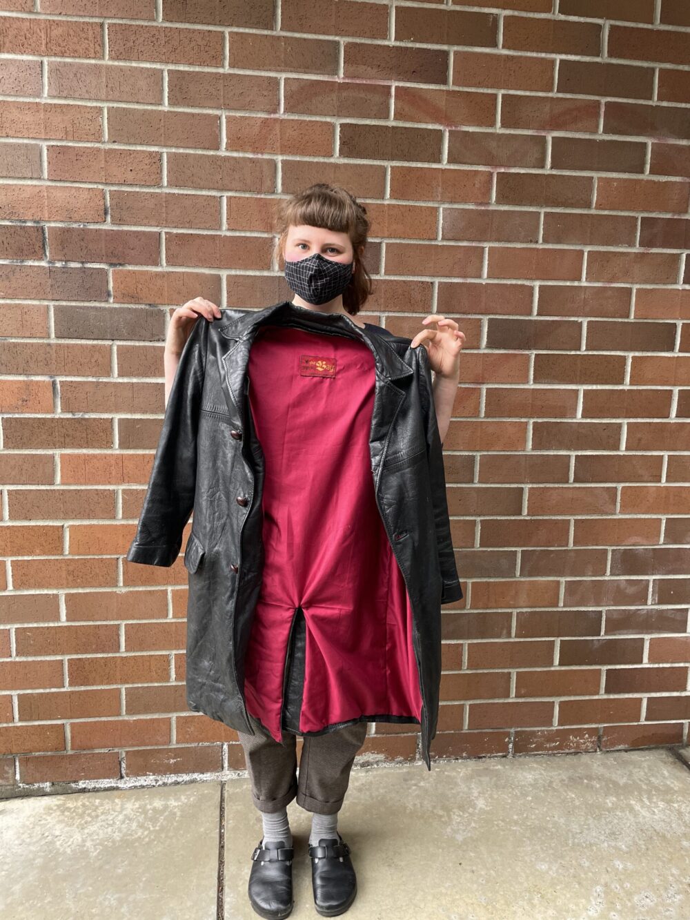 Tess holds up a garment repair of a jacket with a brand new lining