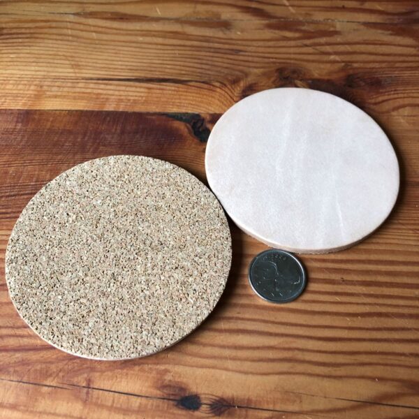 A quarter beside two leather undyed coasters