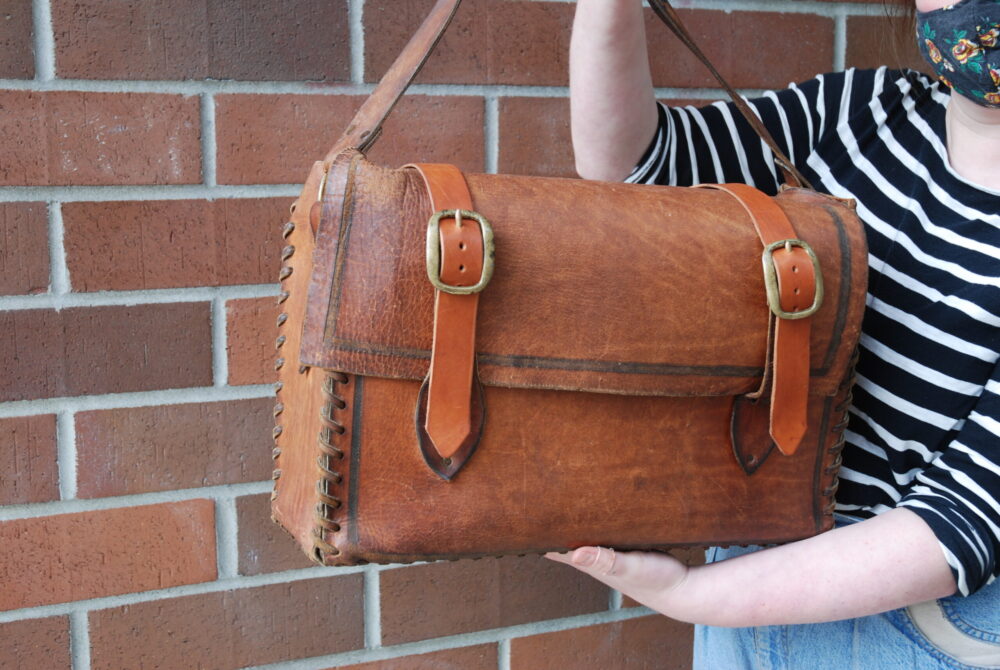 A brown leather satchel with 2 newly remade strap and buckle closures of latigo leather for the main compartment of the bag.
