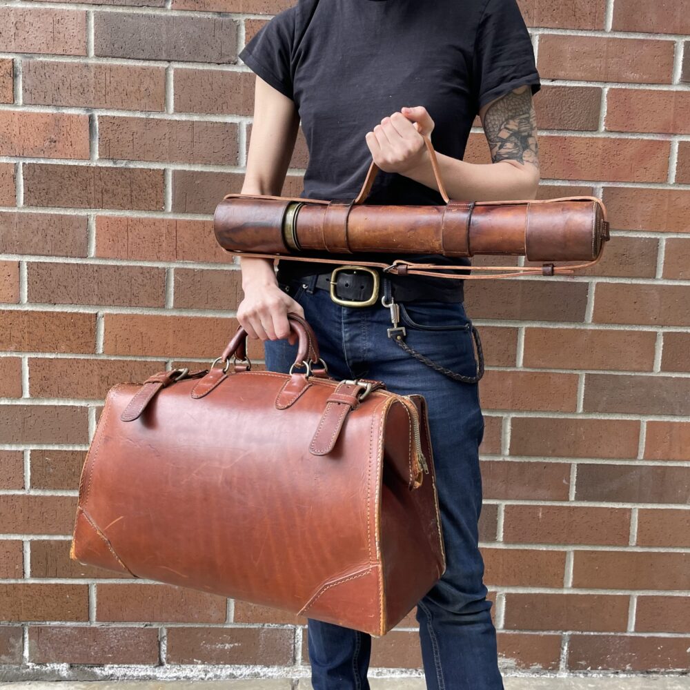 Ariss holding a repaired bag and telescope case with a newly installed strap
