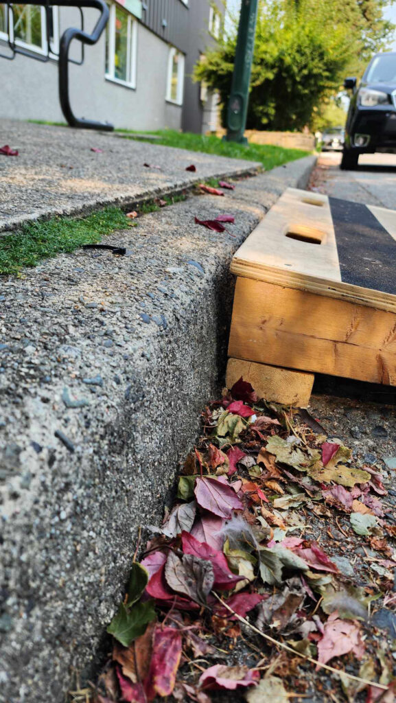 A ground level view of where a wooden accessibility ramp meets the curb