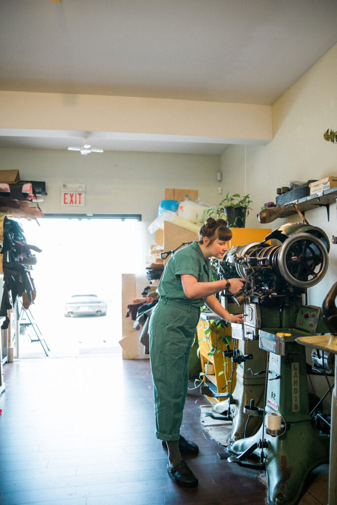 Tess adjusts the outsoler stitching machine in front of open back doors