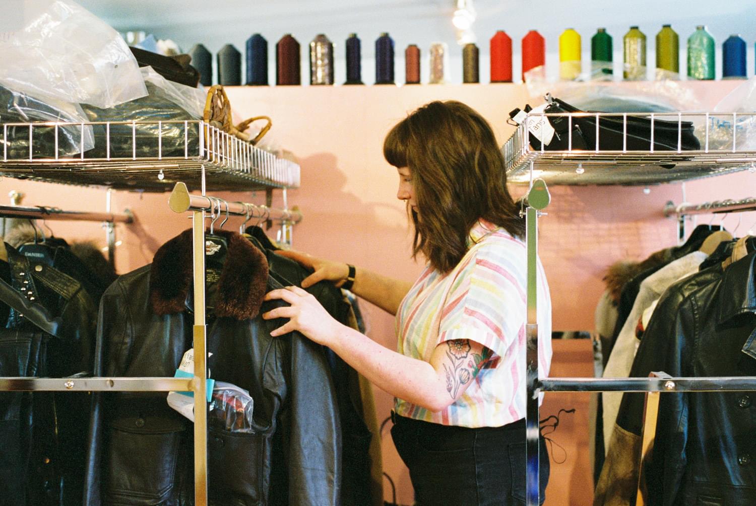 Tess sorts through a rack of items for garment repairs and alterations