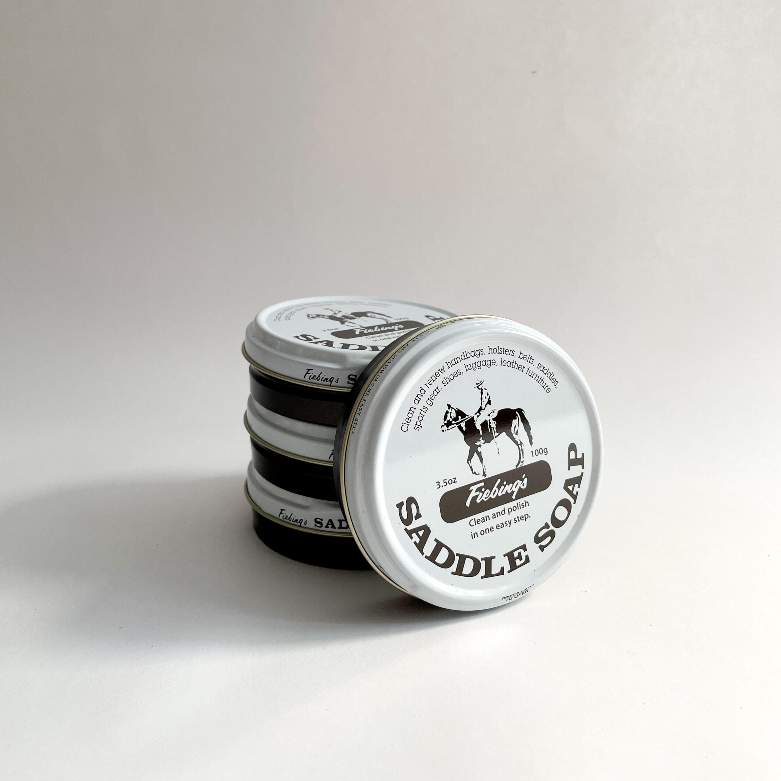 A single can of closed Saddle Soap, leaning against a stack of 3 Saddle Soaps